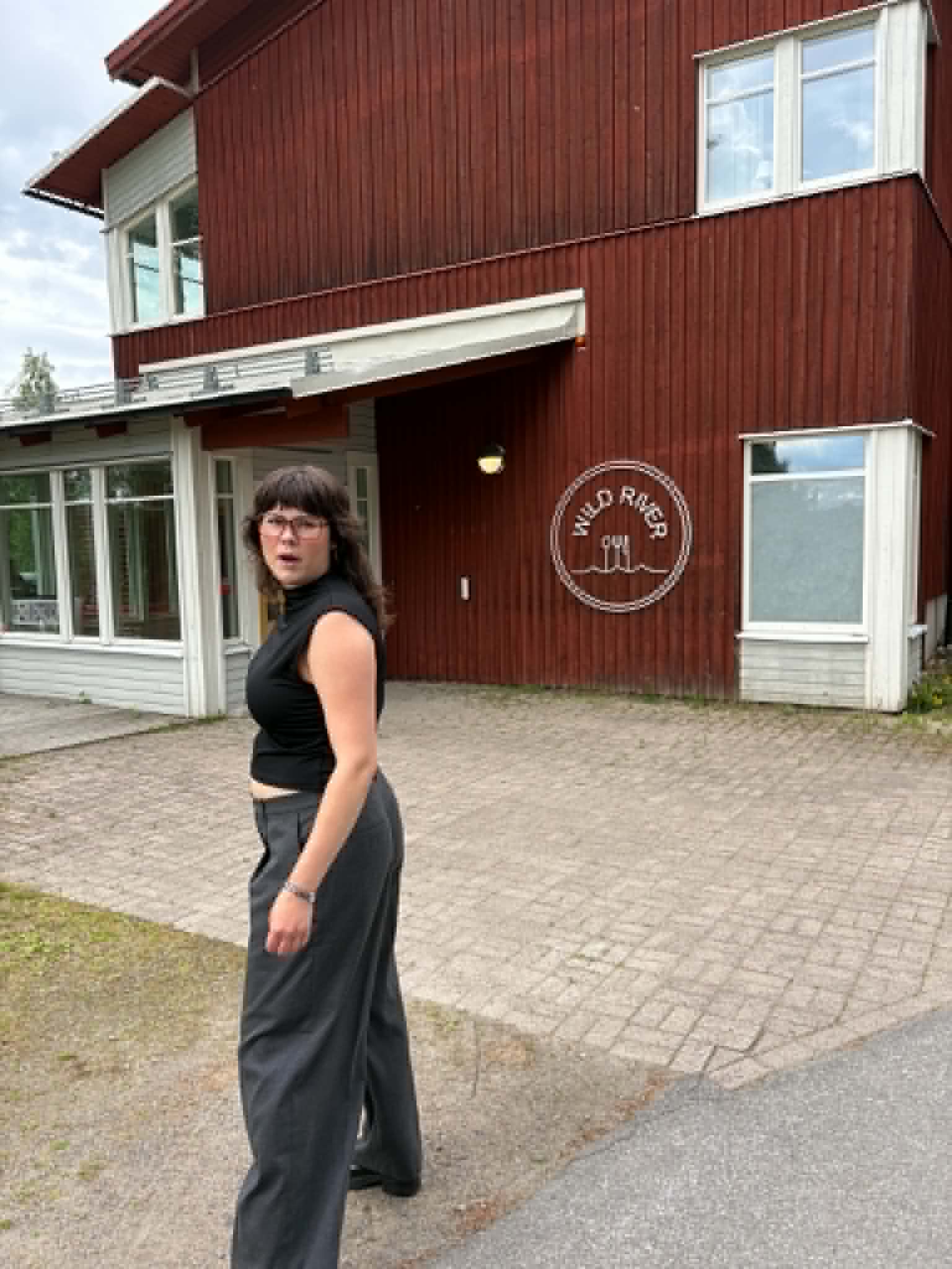Nora som ser förvånad ut framför en röd träbyggnad